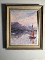 Full view of the framed oil painting showing the sailboat, lake and mountains under cloudy sky.