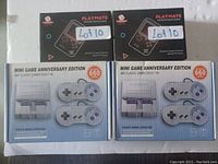Four boxed gaming consoles: two smaller Playmate handheld consoles with 500 built-in games and two larger Mini Game Anniversary Edition consoles with 660 built-in classic games, each including two controllers.