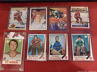 Image showing eight vintage and modern hockey trading cards laid out on a red background, featuring players Eric Lindros, Brad Park, Roy Edwards, Joe Daley, and Ken Broderick.