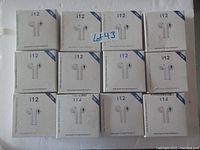 12 sealed retail boxes of i12 wireless Bluetooth earbuds arranged in a 3x4 grid.