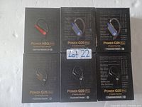 Six boxed earbuds arranged in two rows on a white surface including one Power H8Q Pro box with red accent and five Power Q20 Pro boxes with blue or black accents.