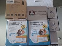 Photo showing two professional pet hair clipper kits, a dog training collar box, two bark collar boxes, and a colorful pet drinking fountain box.