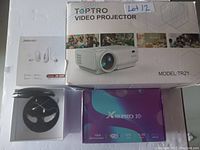 TopTRO Video Projector model TR21 box on right, Jinghao hearing aid device in white packaging on left, X88 Pro 10 TV Box underneath