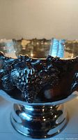 Close up of ornate grape vine decoration on the punch bowl rim, showing detailed clusters and leaves.