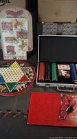 Photo of Rodeo action marble game, Chinese Checkers board, backgammon set boards, checkers pieces, and red velvet piece bag, all displayed together.
