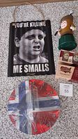 Photo showing the 'You're Killing Me Smalls' metal sign, the Norway flag clock, and other items including the insult comic golf bank and box of shot glasses.