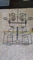 Top view of metal eight-bottle wine holder and three-candle holder on carpet surface.