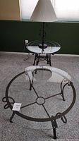 Two glass tables with metal frames and a metal vine lamp in corner of room.