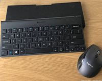 Top view of Logitech foldable keyboard with full keys and Bluetooth enabled mouse on wooden surface.