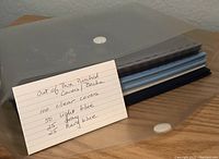 Photo shows stacked translucent and colored punched report covers with a note card detailing quantities and colors.