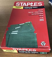 Front box view showing Staples brand standard green hanging file folders, legal size, 25 pack with clear tabs and inserts.