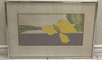 Framed silkscreen print artwork titled 'Just Picked' depicting yellow daffodils against a muted color background in brushed chrome frame.