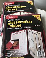 Two sealed packs of red Globe-Weiss Durable Pressboard Classification Folders, each pack containing 5 folders. Visible product info on packaging showing model numbers, folder details including partitions and fasteners.