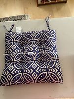 Single outdoor seat cushion with tufted design and ties, showing measurement of 38 cm width with blue and white geometric pattern.