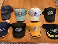 Top-down view of 8 assorted baseball caps showing logos, colors, and details