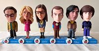 Full set of six The Big Bang Theory bobbleheads lined up on a white surface, each on a blue base with character names.