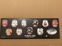 Photo of a plaque displaying nine different hockey sweaters worn by Bobby Orr.