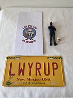 Full photo showing Gus figure, mini fried chicken bucket, Los Pollos Hermanos bag, and New Mexico license plate