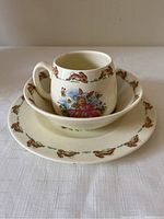 Photo showing teacup placed inside bowl with plate underneath, all displaying matching Bunnykins rabbit designs.