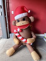 Photo of large inflatable sock monkey with Santa hat and candy cane sitting inside a garage area.
