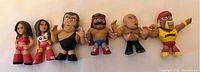 Wide shot of all 6 WWE Funko Mystery Mini figures in a row on a white background showing their size and details.