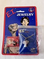Original sealed packaging showing E.T. movie jewelry set with pendant and earrings on vivid branded backing card.