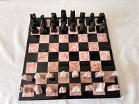 Full chess set arranged on board showing all pieces and the alternating black and pink marble squares on the board