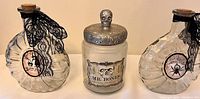 Front view showing all three potion jars in the set: two clear glass with cork stoppers and lace, one white jar with silver skull lid.