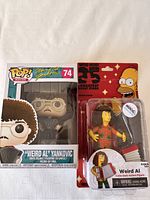 Funko Pop and Simpsons Weird Al figures side by side in packaging with clear view of both items.