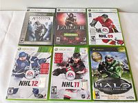 Photo showing six video game cases for Xbox and Xbox 360, arranged in two rows of three.