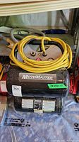 Photo showing full air compressor with yellow hose coiled on top and Motomaster branding on side of black tank.
