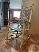 Front‐left view of rocking chair showing turned wood frame and woven seat
