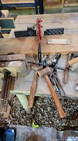 Wide view of wooden clamps, mallets, pliers, pipe cutter on a wooden workbench
