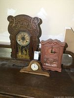 Three clocks displayed together: gingerbread, tambour, ceramic