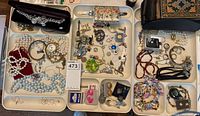 Four plastic trays filled with assorted jewelry pieces including faux pearl necklaces, bead bracelets, pendants, rings, earrings and brooch