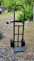 Front view of the black metal dolly showing the tall frame and loading platform.