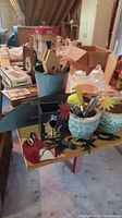 Photo of table with blue metal container, ceramic pots, wooden animal cutouts and gardening tools