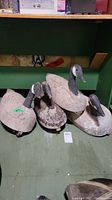 Four wooden goose decoys arranged on floor under table