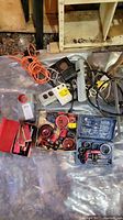 Overall shot showing multiple hole saw kits, extension cord, hanging work light, and electronic timer