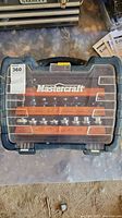 Closed blue plastic carrying case with clear top showing 'Mastercraft' logo and organized router bits visible inside.