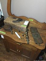 Lot displayed on wooden washstand showing all items including small wood box, pulley, brass thermometer, dairy scale, brass spigot, and wood crate.