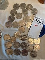 Overhead shot of 30 circulated Canadian silver dollars laid on cloth with a numbered card showing quantity