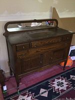 Front view of oak sideboard with curved wood-framed mirror on back.