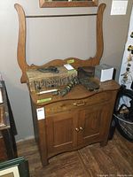 Front view of solid wood washstand with attached back harp, drawer and cabinet, surface with items removed.