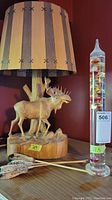Both the carved moose lamp and Galileo thermometer side by side on shelf