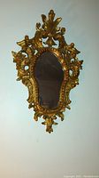 Full front view of antique gilt gold hand-carved wood mirror showing entire frame and reflective glass surface.