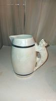 Side angle showing cat-shaped handle and body of pearl lustre jug with black bands