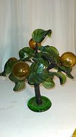 Front view of the Murano glass orange tree showing orange spherical fruits and green leaves on a green circular base.