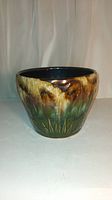 Full view of the antique Roseville plant pot showing sunburst design and glazed multicolor pattern.