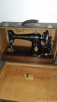Machine inside wooden carrying case with lid open and handle visible